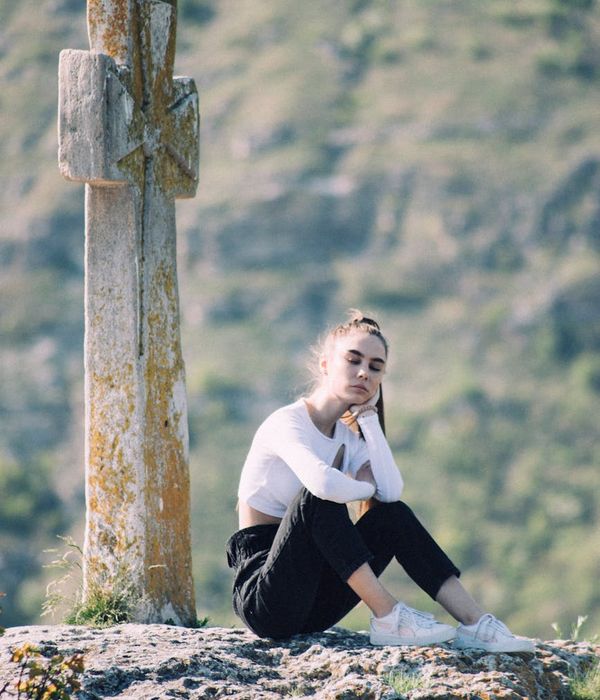 A person sitting calmly with eyes closed in a meditation pose, surrounded by soft natural light.